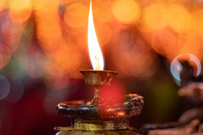 Close-up of illuminated burning candles in temple