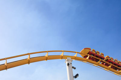 Low angle view of rollercoaster against blue sky