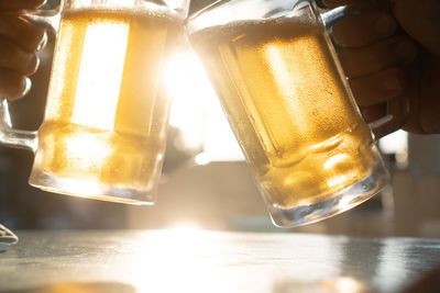 Close-up of hand holding beer glass on table