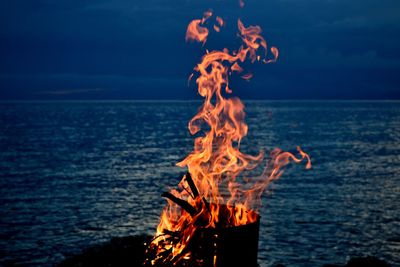 Close-up of bonfire on shore against sky
