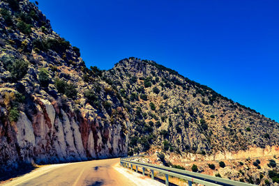 Road by mountain against clear blue sky