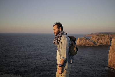 Man standing at sea shore against clear sky