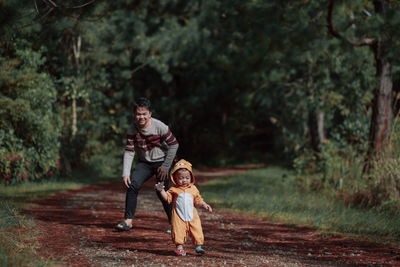 Full length of father and son on tree against plants