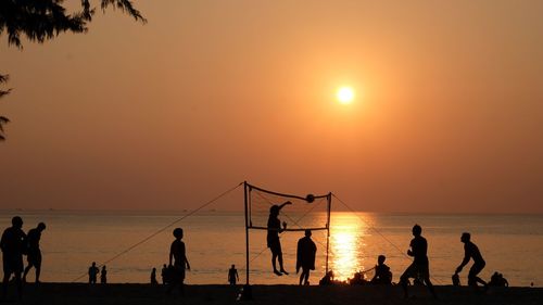 Silhouette people playing on beach against sky