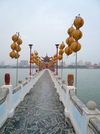 Lanterns hanging by sea against sky