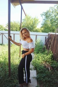 Portrait of smiling young woman standing against trees