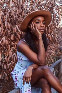 Young woman looking away while sitting on tree