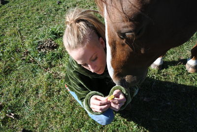 High angle view of young woman with horse on field