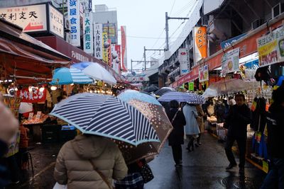 People walking on street in city during rainy season