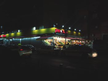 Cars on illuminated city against sky at night