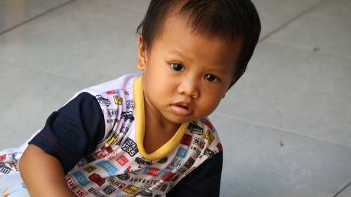 Portrait of cute baby boy sitting on floor