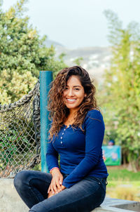 Portrait of young woman sitting on retaining wall