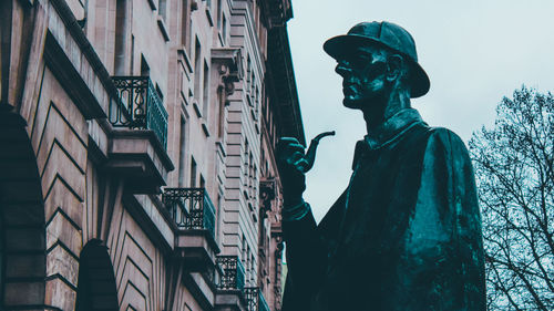 Low angle view of sherlock statue against buildings in the city of london