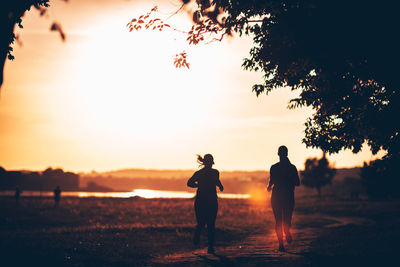 Silhouette women running on field against sky during sunset