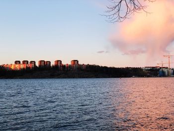 Buildings by sea against sky during sunset