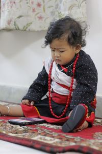 Cute girl sitting and watching mobile phone at home