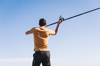 Rear view of man standing against clear sky