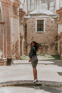 Full length portrait of woman standing against building in city