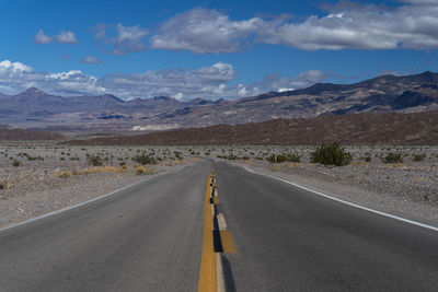 Empty road along landscape and mountains against sky