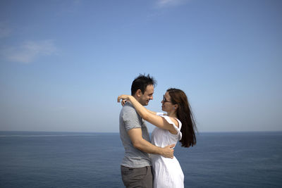 Young couple standing in sea against sky