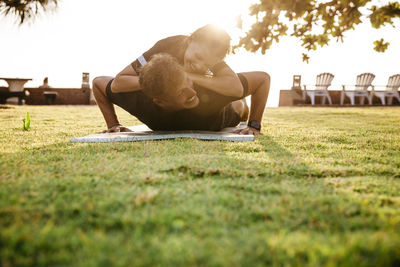 Smiling father carrying daughter on back while exercising in park during sunset