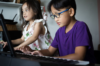 Happy kids playing piano at home