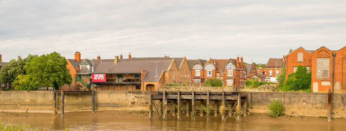 Bridge over river by buildings against sky