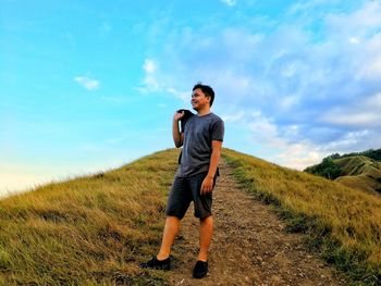 Full length of smiling man standing on field against sky