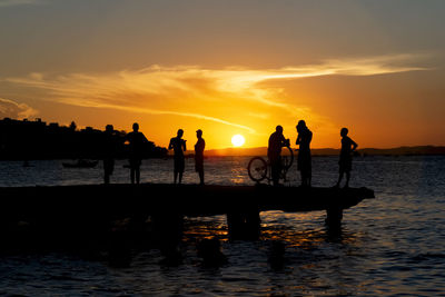 Silhouette people at beach during sunset