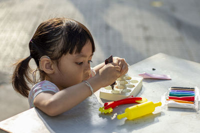 Close-up of cute girl playing with childs play clay at table outdoors