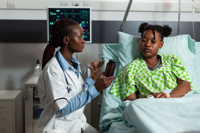 Portrait of female friends using mobile phone while sitting at clinic