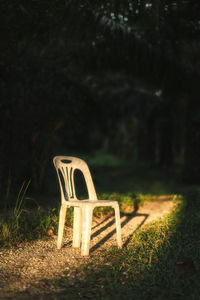 Chair on field against trees at night
