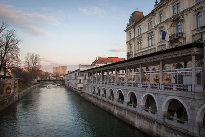 Bridge over river amidst buildings in city against sky