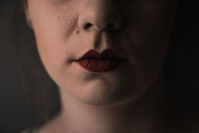Mysterious portrait of a young female with red lipstick and only half of the face showing