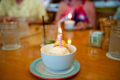 Close-up of birthday candle in ice cream bowl on table