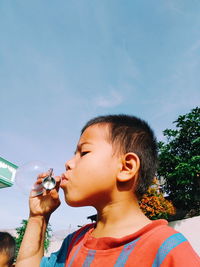 Portrait of boy drinking water from bottle against sky