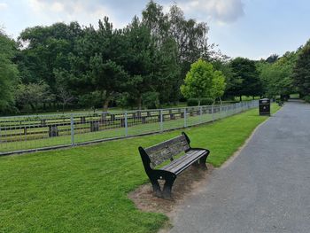 Empty bench in park against sky