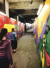 Rear view of people in graffiti on wall