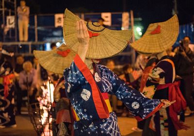 Women wearing traditional clothing dancing in city at night