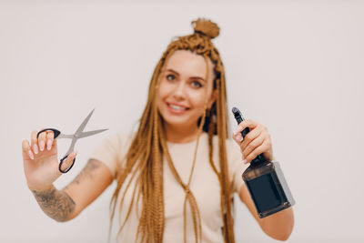 Portrait of hairdresser holding scissors against white background