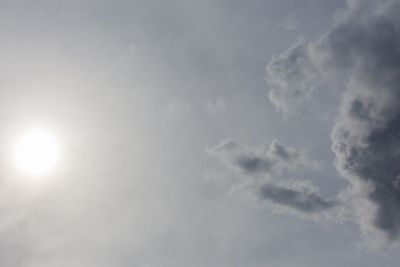 Low angle view of sun shining through clouds