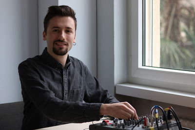 Portrait of young man against window