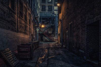 Illuminated street amidst buildings at night