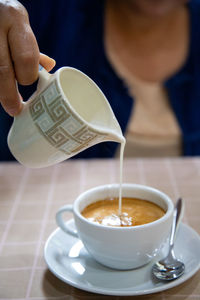 Midsection of woman holding coffee on table