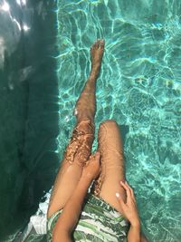 Low section of woman relaxing in swimming pool