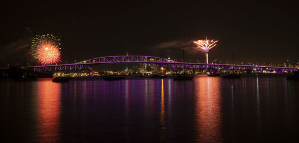 Illuminated bridge over river against sky at night