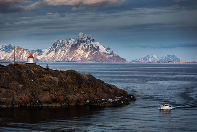 Scenic view of boat in sea by mountains against sky