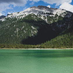 Scenic view of sea by mountains against sky