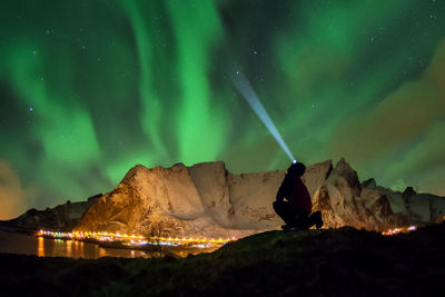 Silhouette of man with illuminated flashlight at night