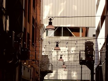 Low angle view of lights hanging amidst buildings in city